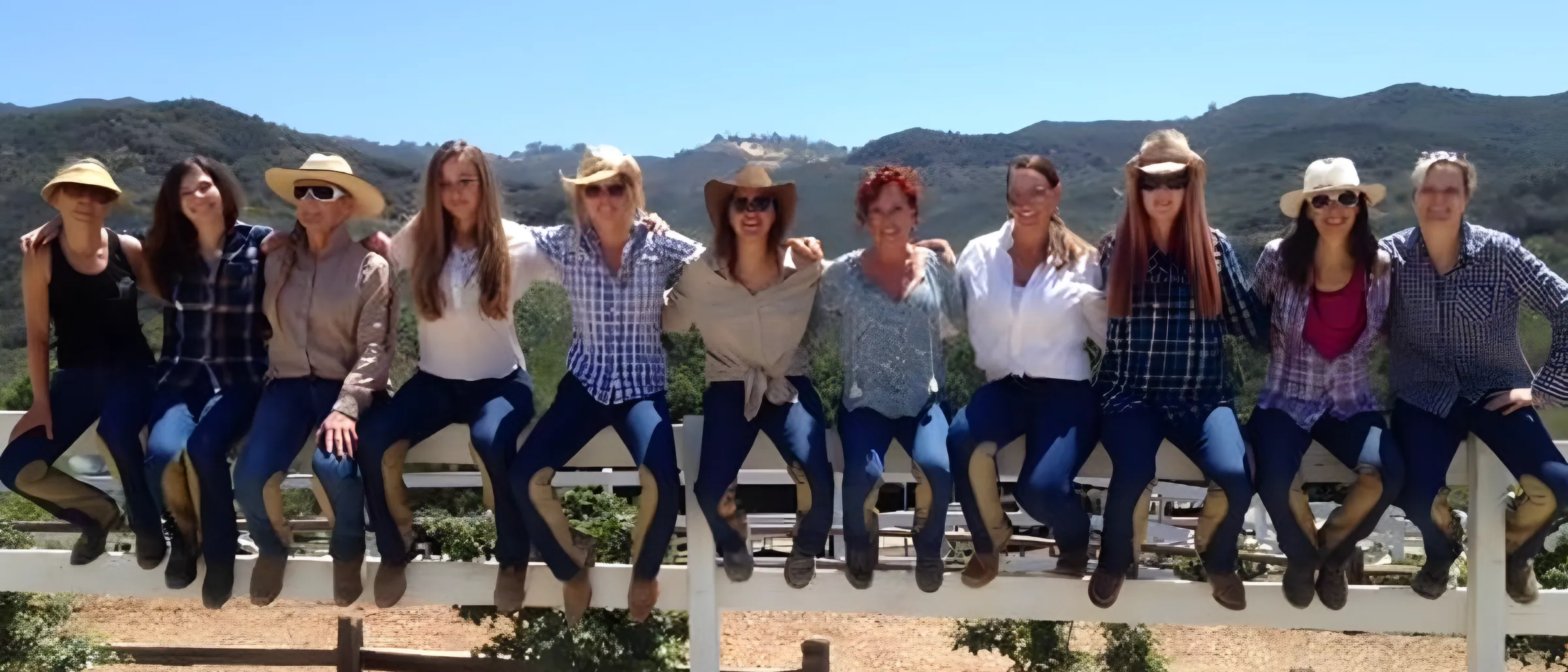 The ranch crew lined up on the fence in hats