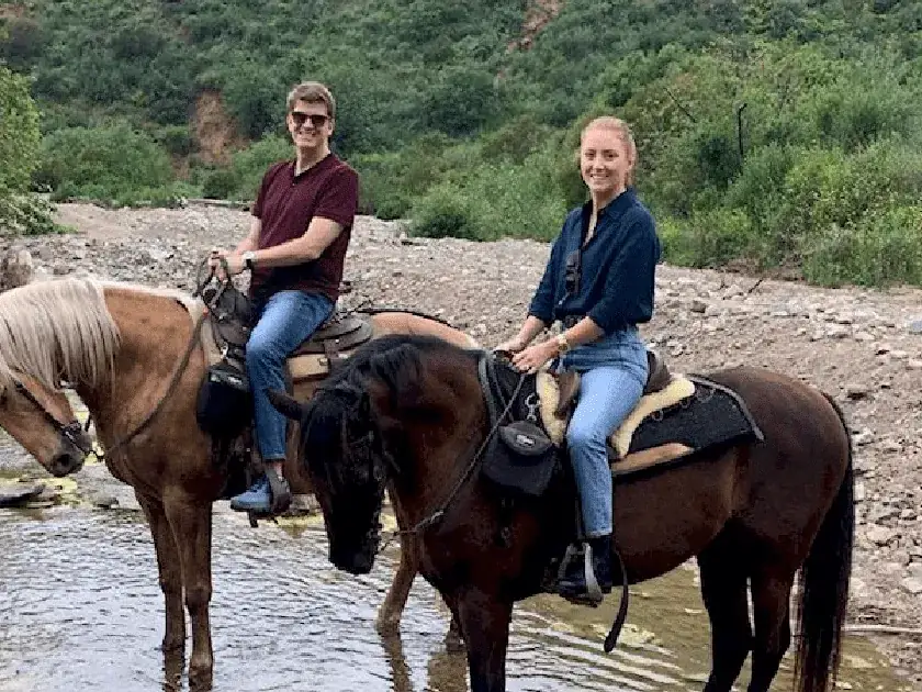 A couple riding through the creek