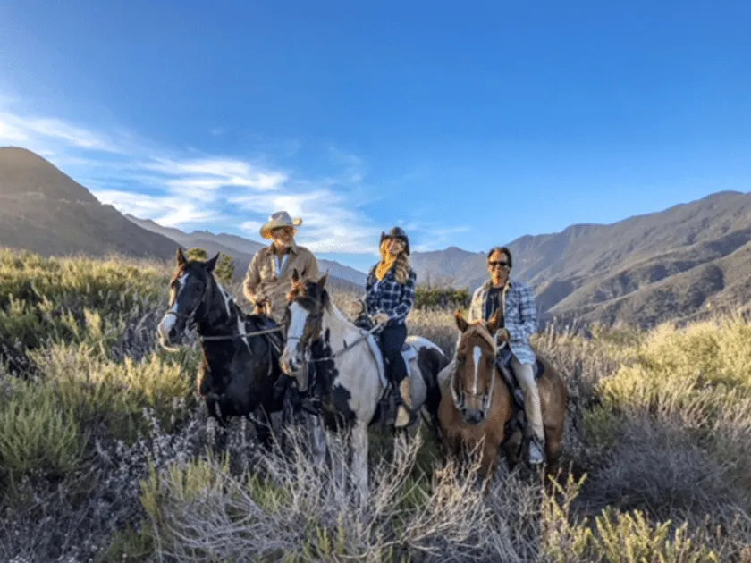 Four riders with the mountains behind