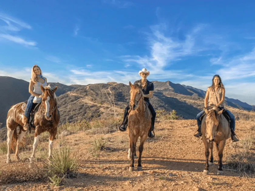 Three riders on the trail under a blue sky