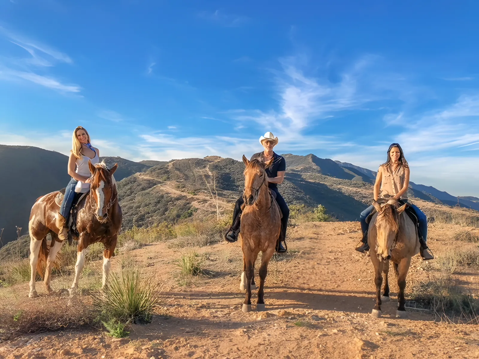 Three riders side by side on the ridge under a blue sky