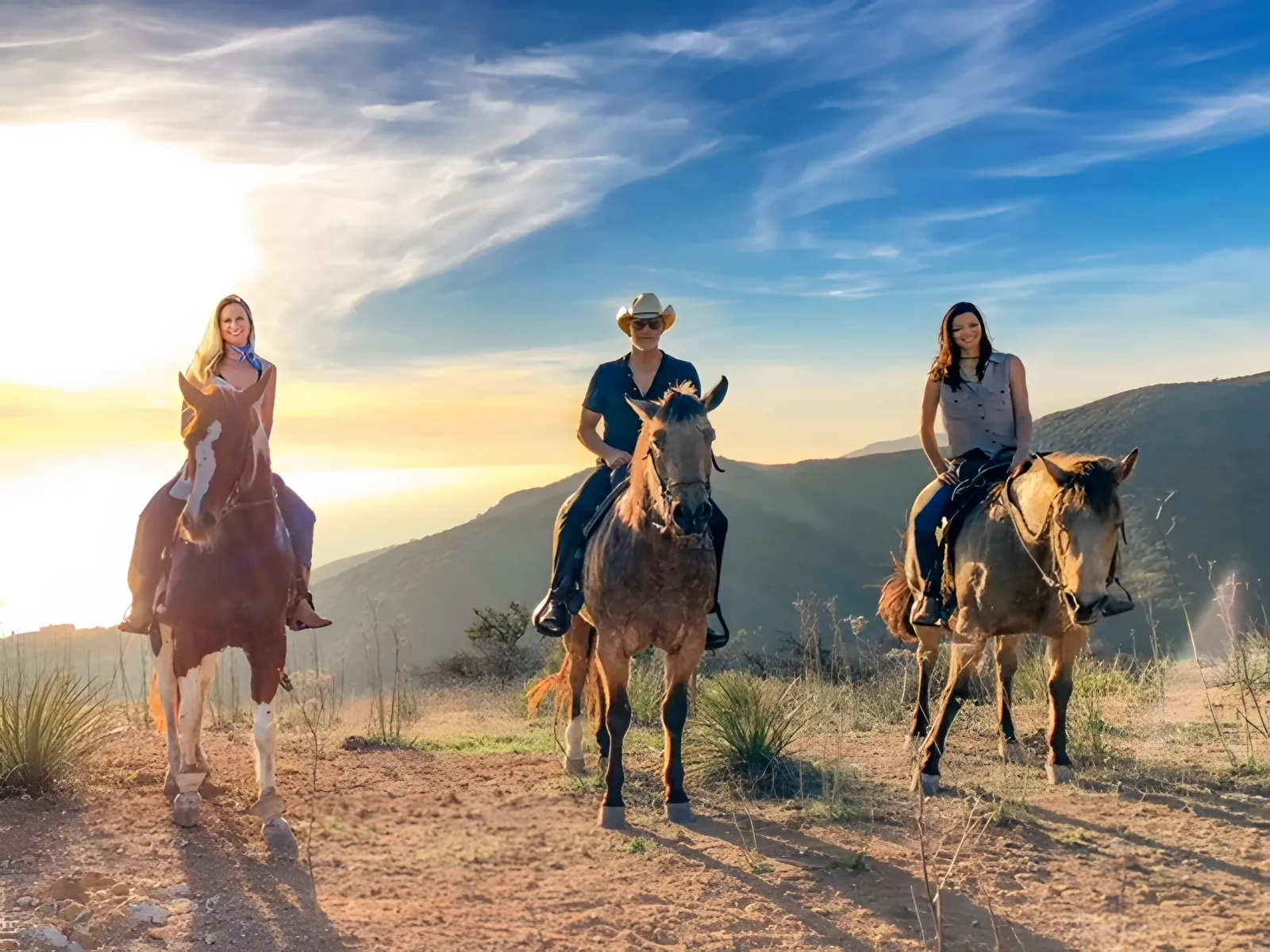 Three riders side by side on the ridge in golden light