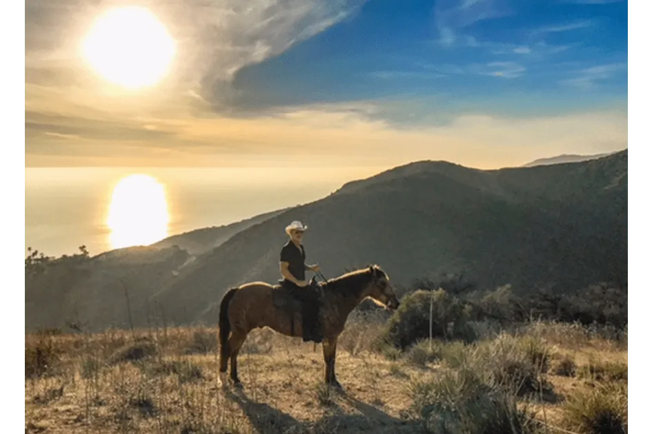 A rider at sunset with the sun on the water